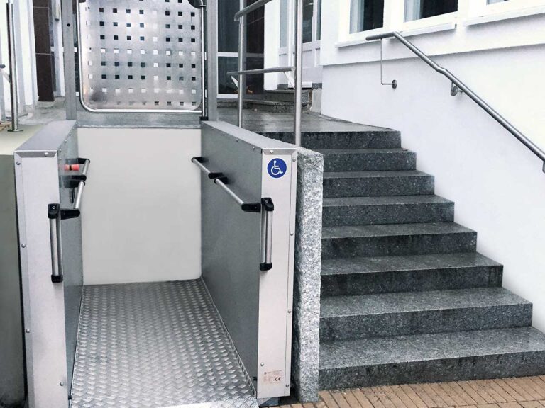 Eingebauter grauer sani-trans Hublift HB 1300 im Außenbereich zur Schaffung von Barrierefreiheit für Menschen mit eingeschränkter Mobilität (Frontansicht)